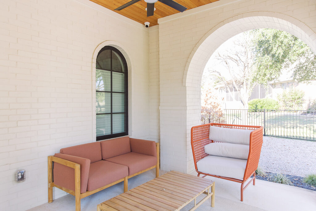 Five Oaks Custom Builders - home renovation with custom design and styling for central texas - exposed natural wood accents and warm minimalism - front porch of a white brick home with arched pillars and outdoor seating