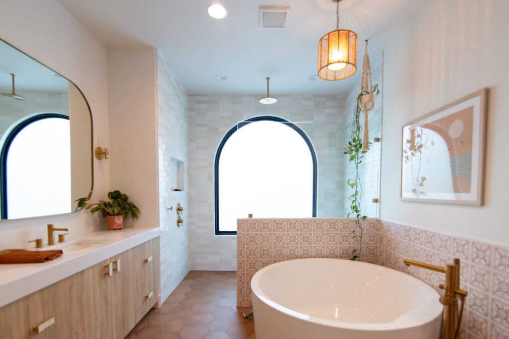 Five Oaks Custom Builders - home renovation with custom design and western styling for central texas - tile accents and warm minimalism - updated bathroom with brass gold metallic fixtures and round standalone tub - arched window