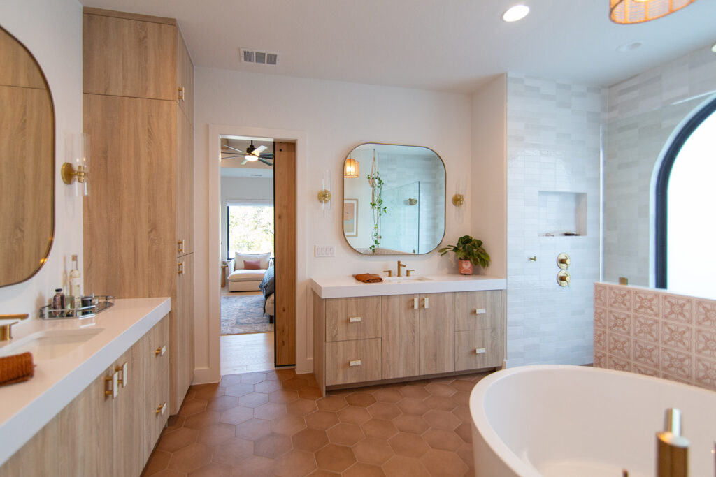 Five Oaks Custom Builders - home renovation with custom design and western styling for central texas - tile accents with wooden storage and warm minimalism - updated bathroom with brass gold metallic fixtures and round standalone tub