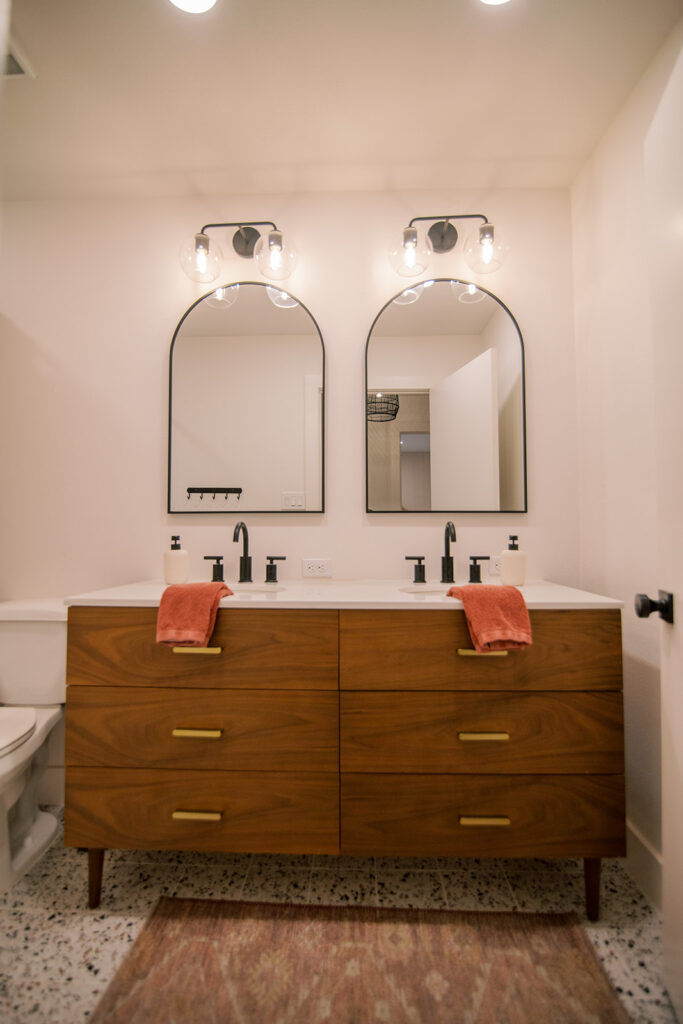 Five Oaks Custom Builders - home renovation with custom styling for central texas - exposed natural wood accents and warm minimalism - master bathroom with jack and jill sink and arched mirrors - black fixtures and minimal masculine styling